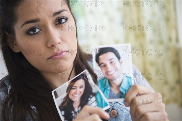 Woman holding torn picture of herself with ex-boyfriend