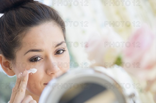 Woman applying moisturizer in mirror