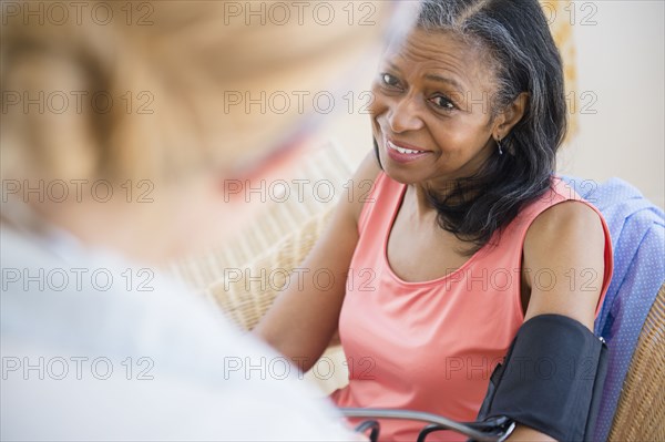 Woman having blood pressure taken on sofa