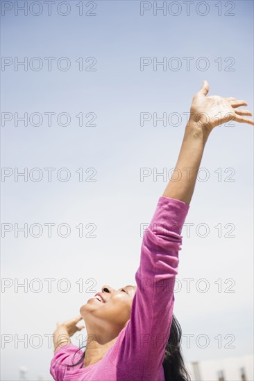 Mixed race woman with arms outstretched outdoors