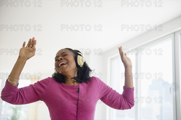 Mixed race woman listening to headphones in living room