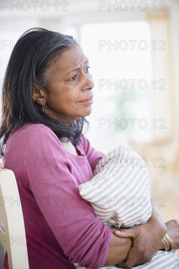 Sad mixed race woman hugging pillow