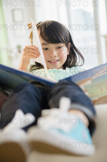 Filipino girl reading book on sofa