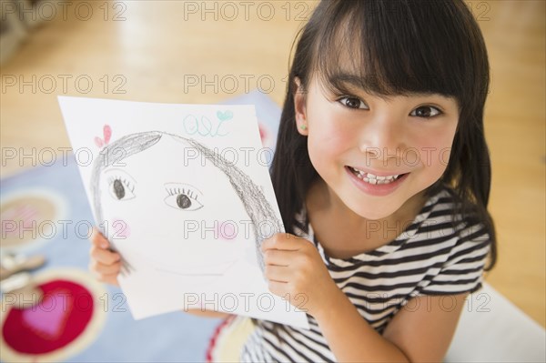 Filipino girl displaying drawing in bedroom