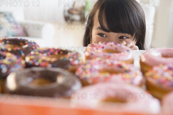 Filipino girl peering at donuts on table