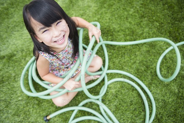 Filipino girl playing with hose in backyard