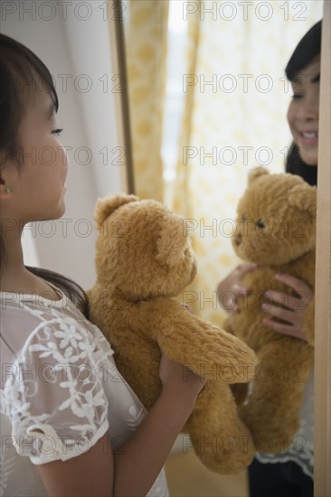 Filipino girl admiring teddy bear in mirror