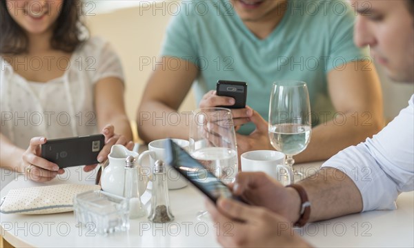 Hispanic friends using cell phones in cafe