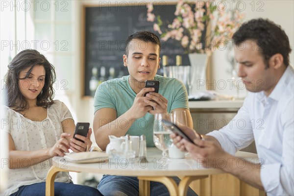 Hispanic friends using cell phones in cafe