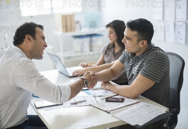 Hispanic businessmen shaking hands in office