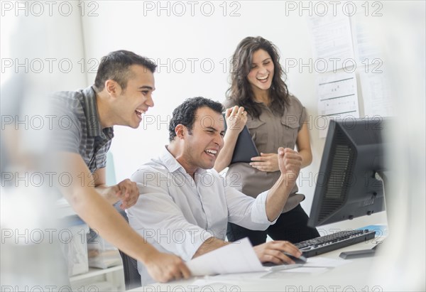 Hispanic business people cheering together in office