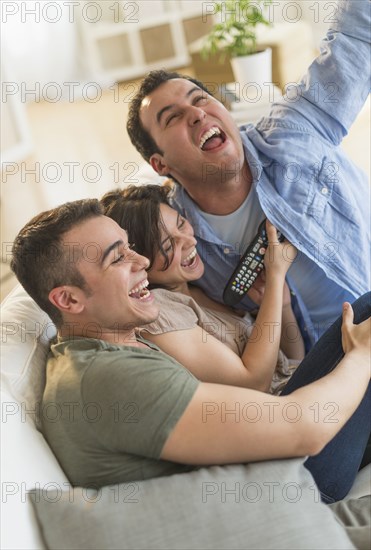 Hispanic friends cheering at television in living room