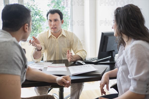 Hispanic businessman talking to clients in office