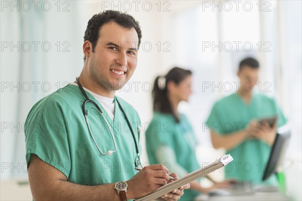 Hispanic nurse reading medical chart in hospital