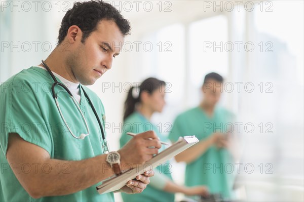 Hispanic nurse reading medical chart in hospital