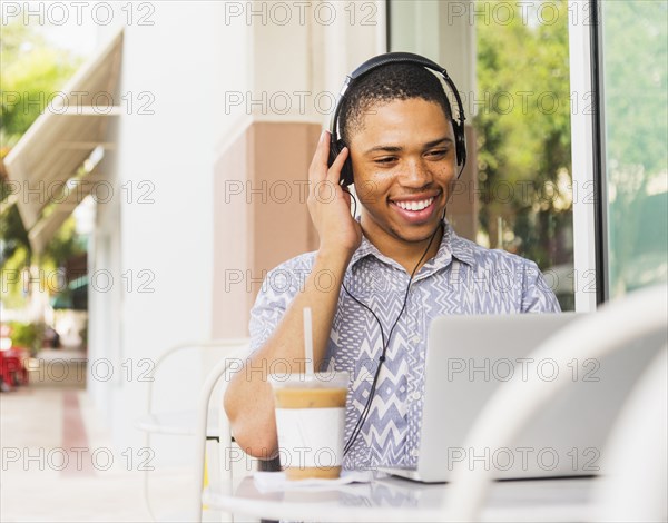 African American man using laptop at sidewalk cafe