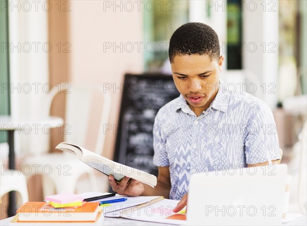 African American man studying at sidewalk cafe