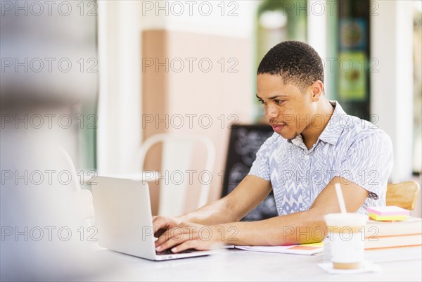 African American man using laptop at sidewalk cafe