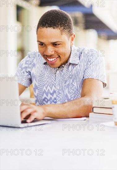 African American man using laptop at sidewalk cafe