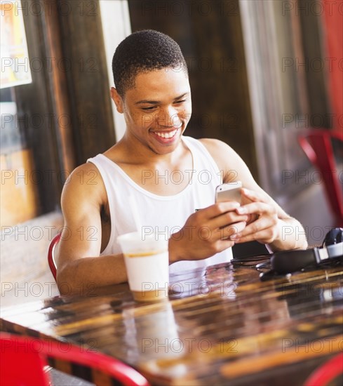 African American man using cell phone at cafe