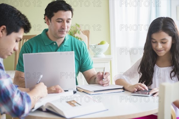 Hispanic family doing homework together at table