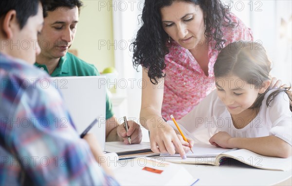 Hispanic family doing homework together at table