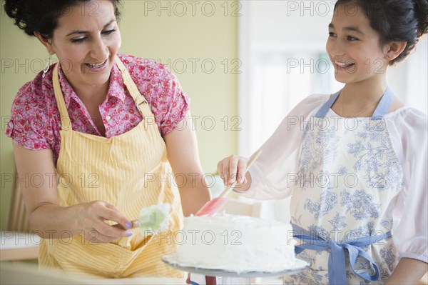 Hispanic mother and daughter decorating cake together