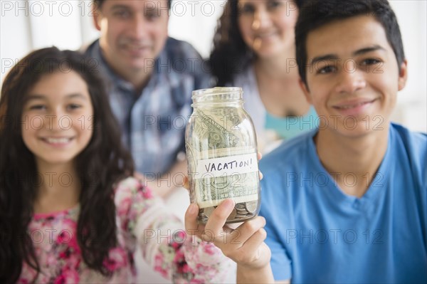 Hispanic family holding full vacation savings jar