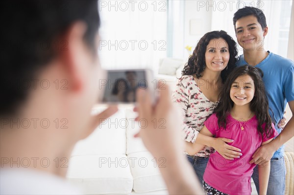 Hispanic family taking cell phone photograph in living room