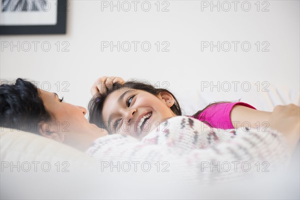 Hispanic mother and daughter relaxing together on bed