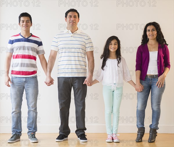 Smiling Hispanic family holding hands