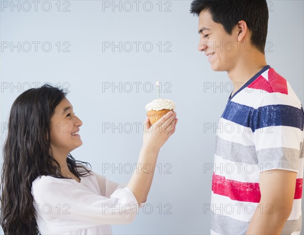 Hispanic brother and sister celebrating birthday with cupcake