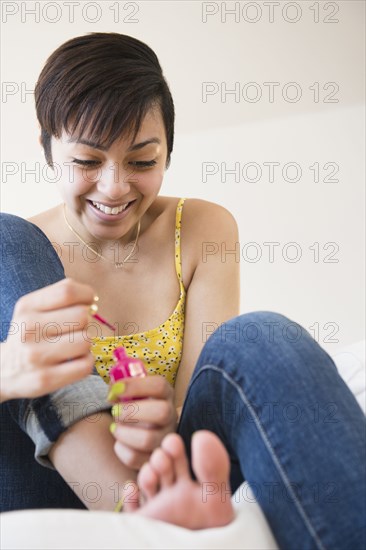 Mixed race woman painting her toenails