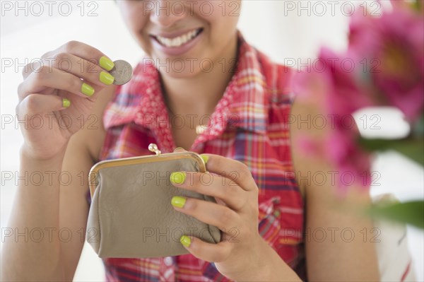 Mixed race woman putting coin into purse