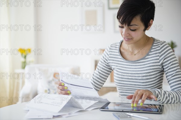 Mixed race woman paying bills on digital tablet