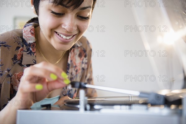 Smiling mixed race woman playing vinyl record