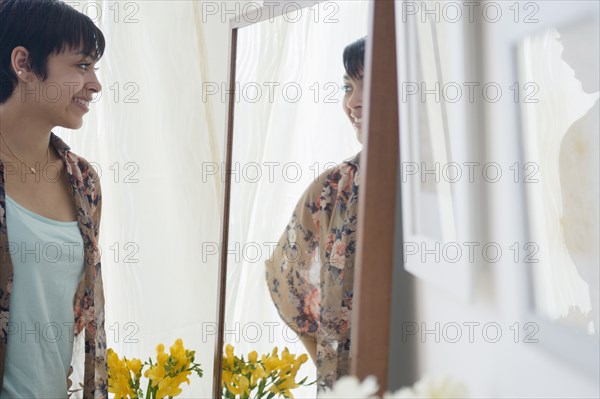 Smiling mixed race woman admiring herself in mirror