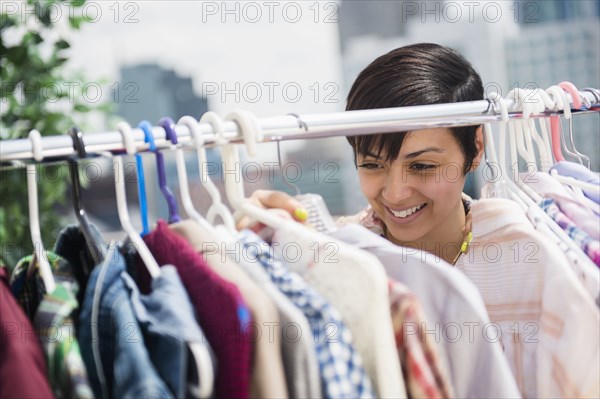 Mixed race woman examining clothing on rack