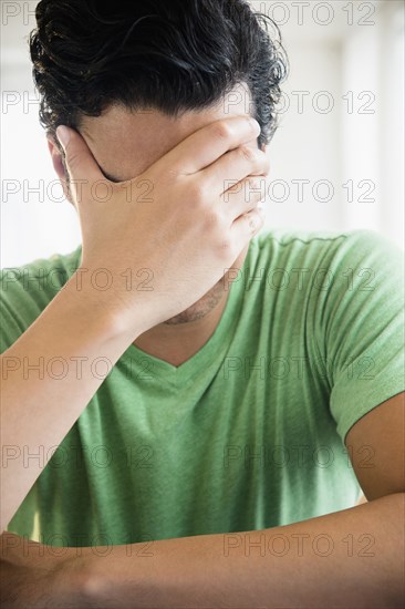 Frustrated mixed race man covering his face