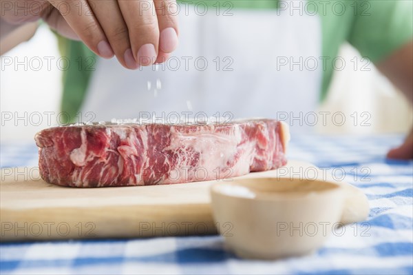Close up of mixed race man sprinkling salt on steak