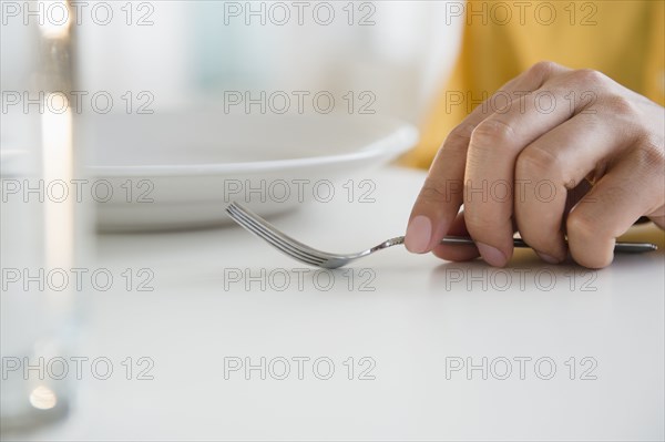 Close up of mixed race man holding fork at table