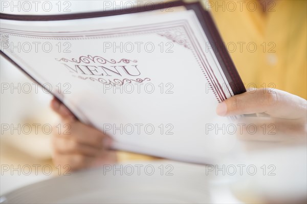 Close up of mixed race man reading menu in restaurant