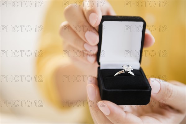 Mixed race man holding engagement ring in box