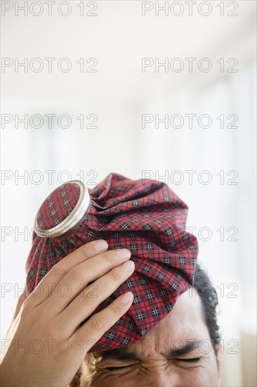 Mixed race man holding ice pack to head