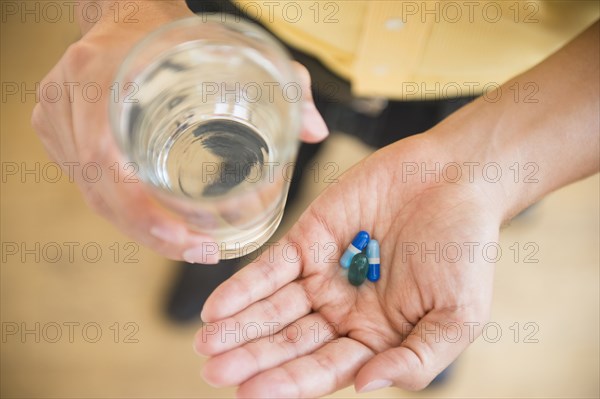 Close up of mixed race man holding medicine and glass of water