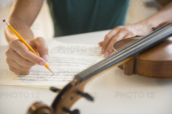 Close up of mixed race man writing sheet music for violin