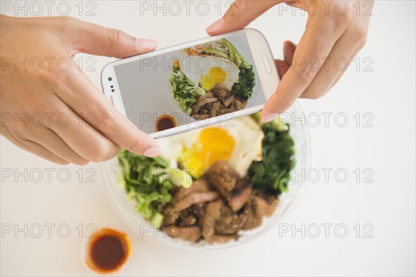 Close up of mixed race man photographing food with cell phone