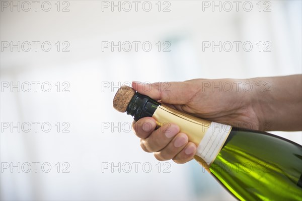 Close up of mixed race man opening bottle of champagne