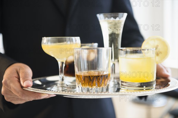 Close up of mixed race waiter holding tray of drinks