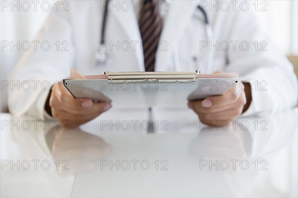 Close up of mixed race doctor holding clipboard